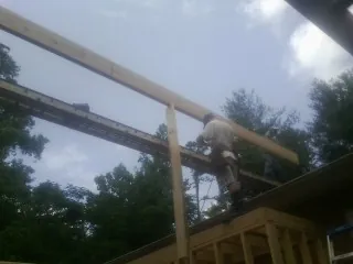 Carpenter setting a ridge beam over a new addition frame — Ice Dam Removal by Roofing Brothers in Inwood