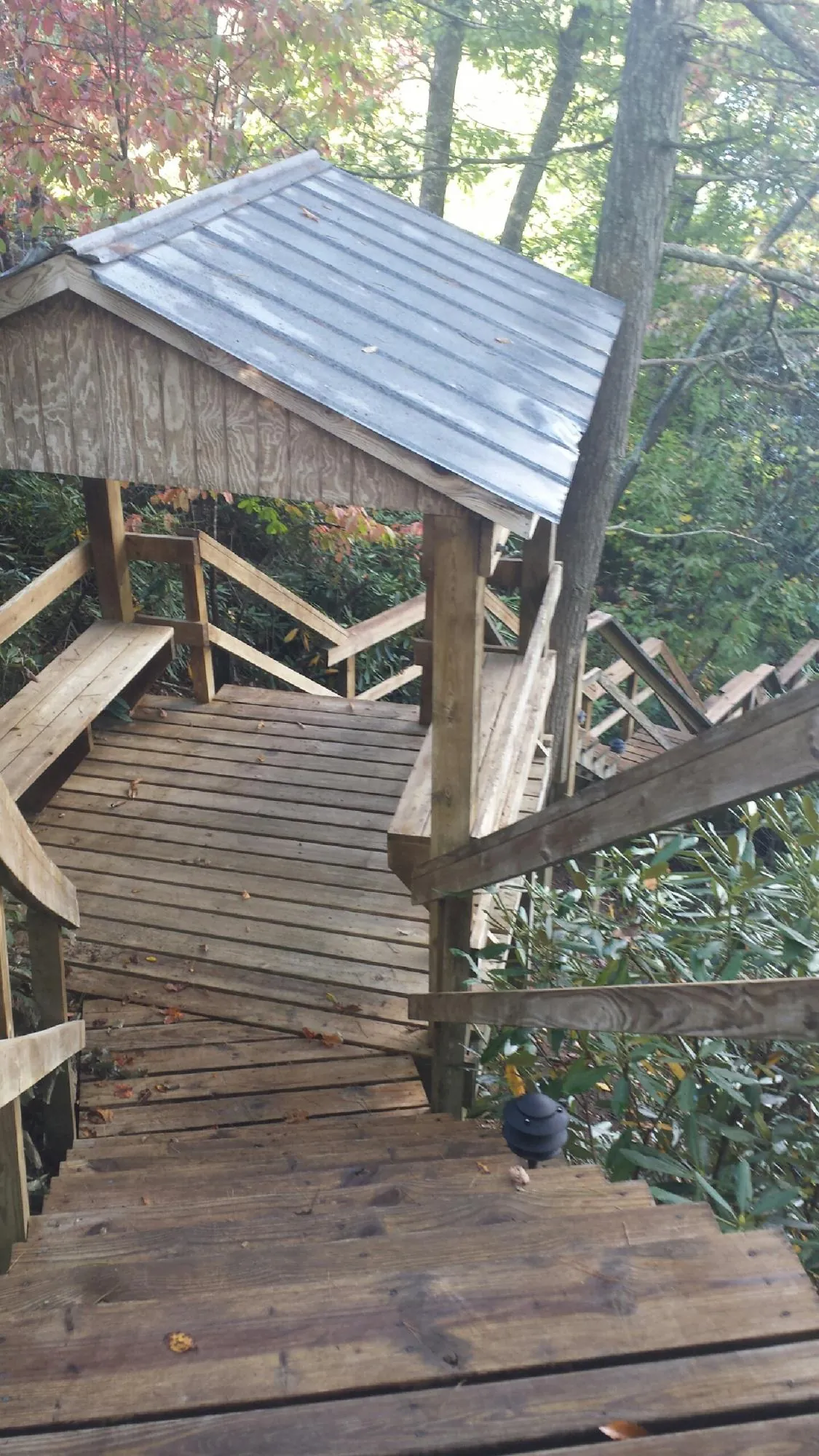 Metal roofed shelter over wooden steps on a wooded walkway — Skylight Repair & Installation work by our crew in Inwood